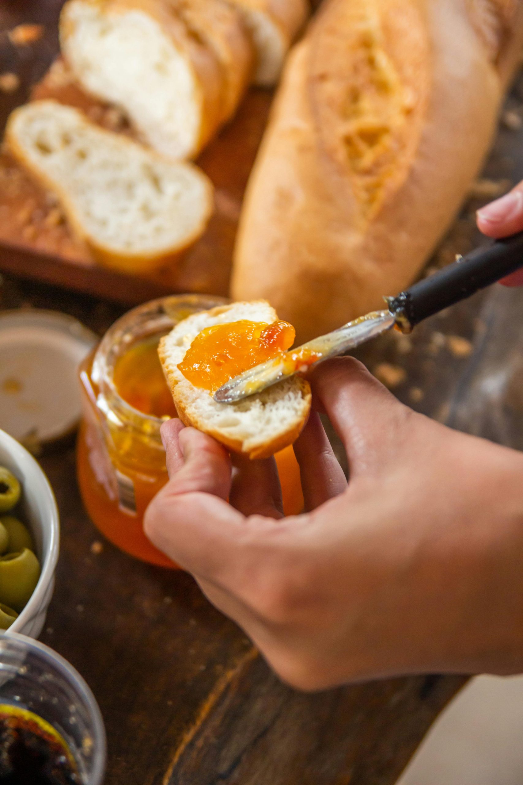 A close-up of hands spreading apricot jam on fresh bread, ideal for breakfast theme.