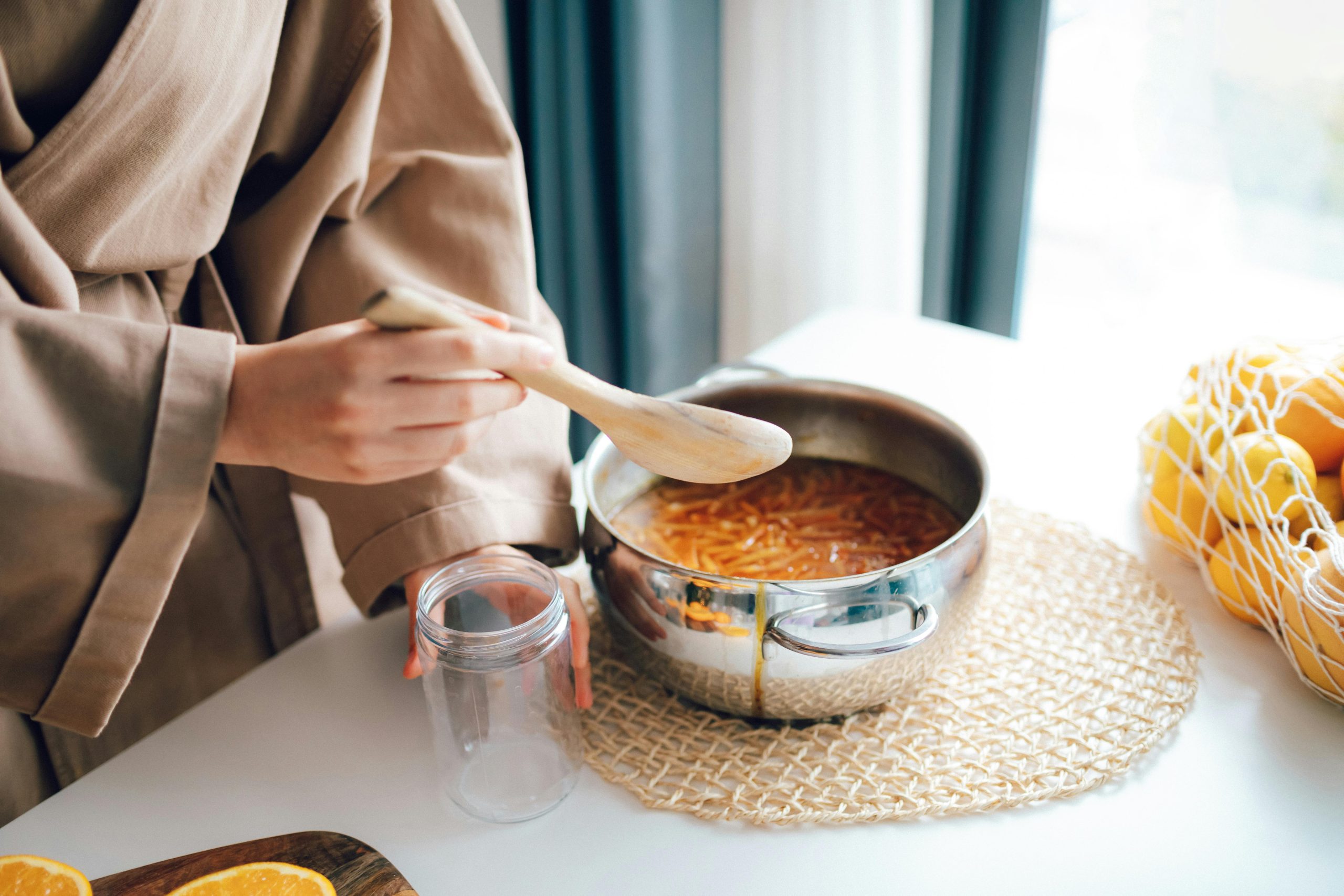 Woman preparing citrus jam in the kitchen with fresh ingredients.